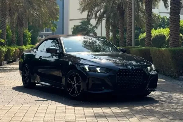 Black BMW 4 Series coupe parked beside palm trees in sunny Dubai