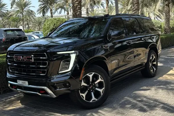 Black GMC Yukon parked beside palm trees in Dubai
